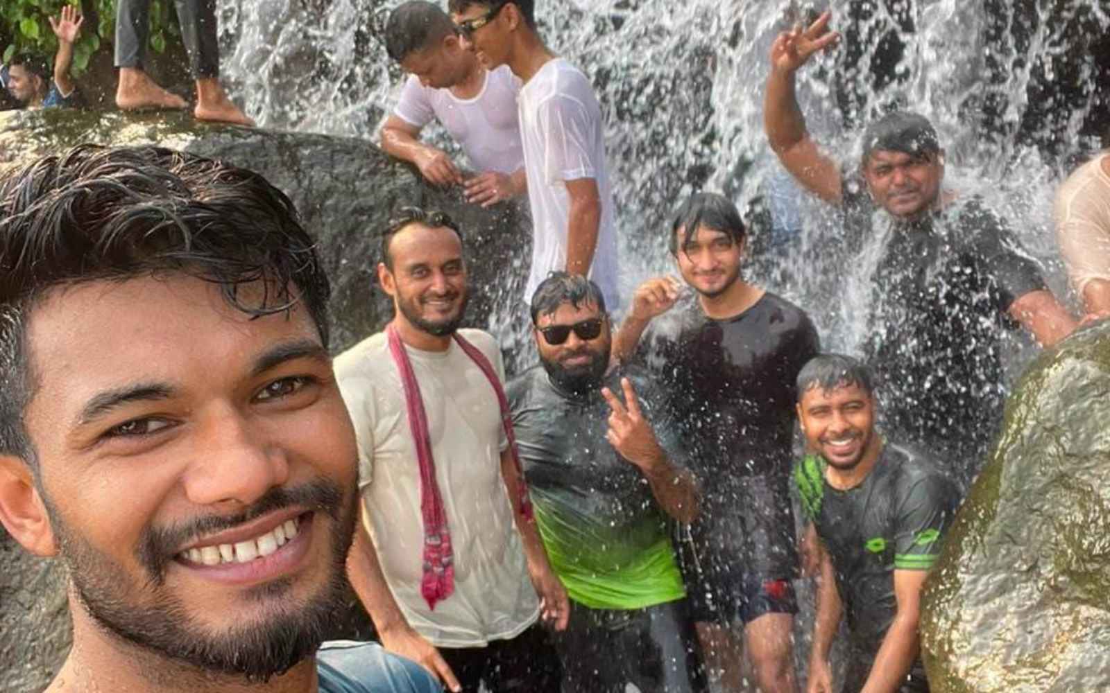 The team soaked and laughing under the waterfall
