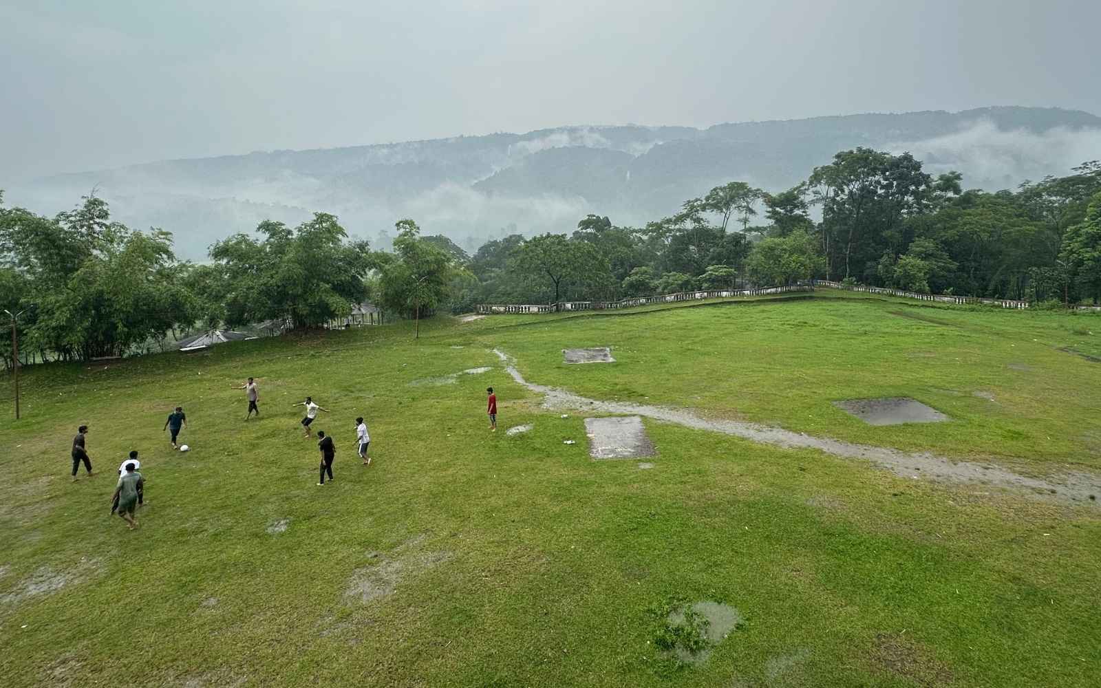 The team playing football on a wet green ground, mist rolling over the hills behind